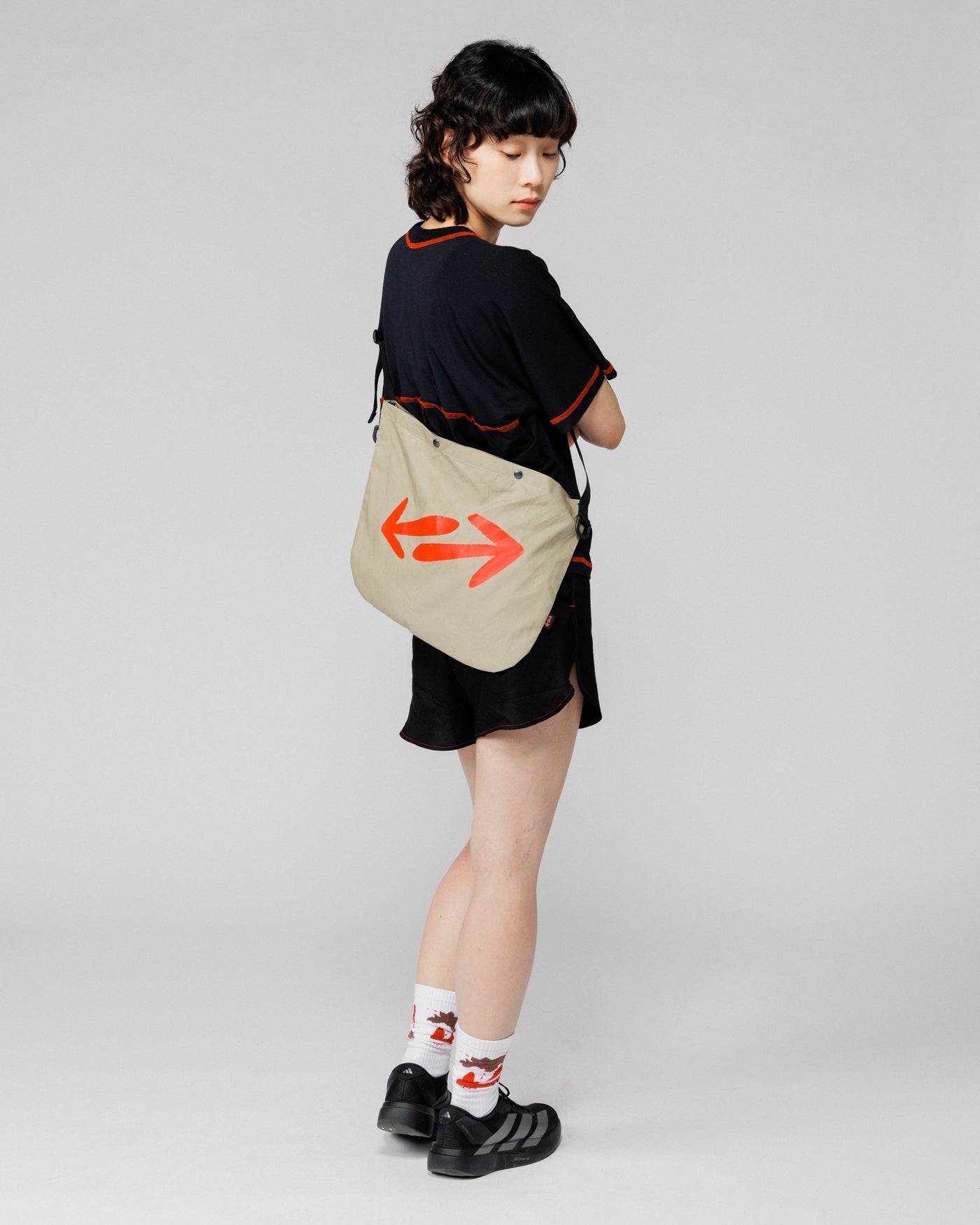 Outnback Musette in stone worn across the back, full-body rear view on model showing double arrow logo