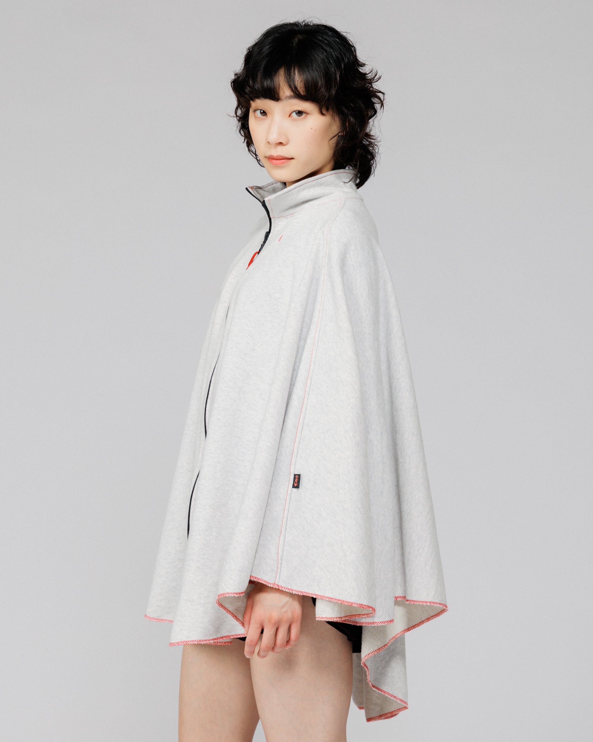 Cropped side view of the Outnback Recovery Cape in marl grey showing the arrow logo tab
