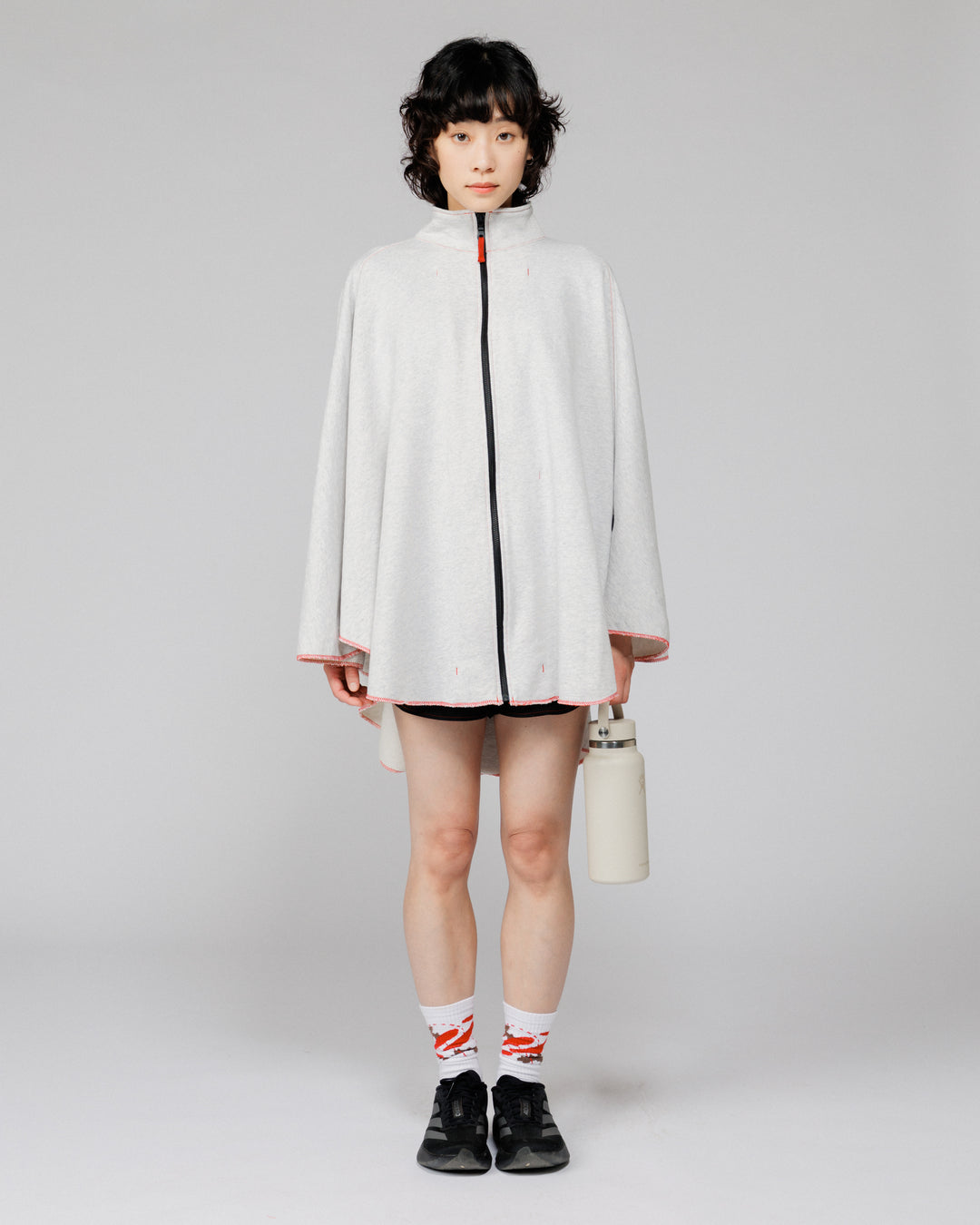 Model wearing the Outnback Recovery Cape in marl grey, front view, zipped with collar up