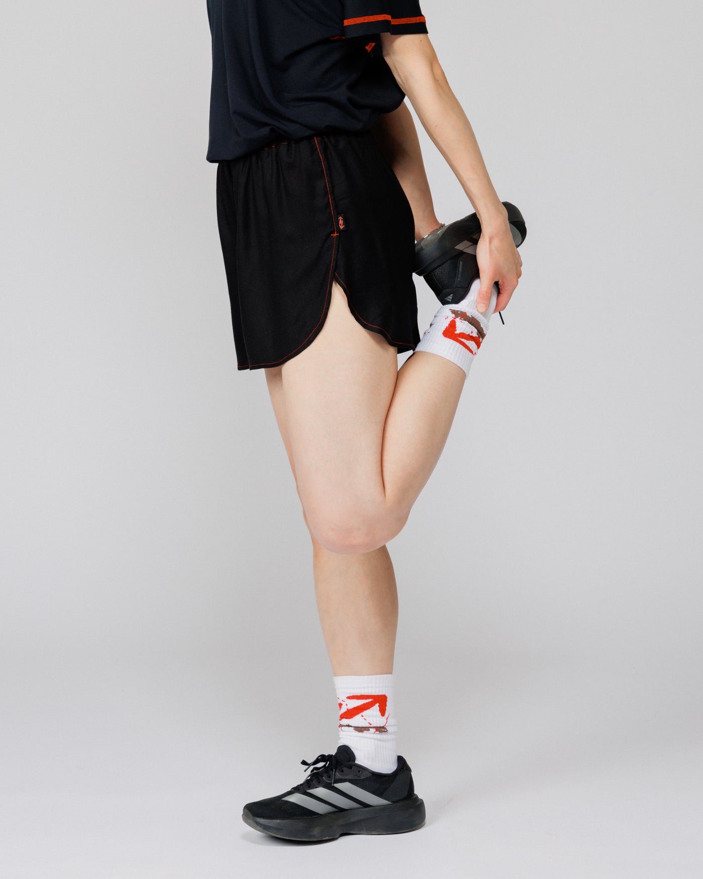 Outnback Running Short in black, cropped view on model lifting a running shoe